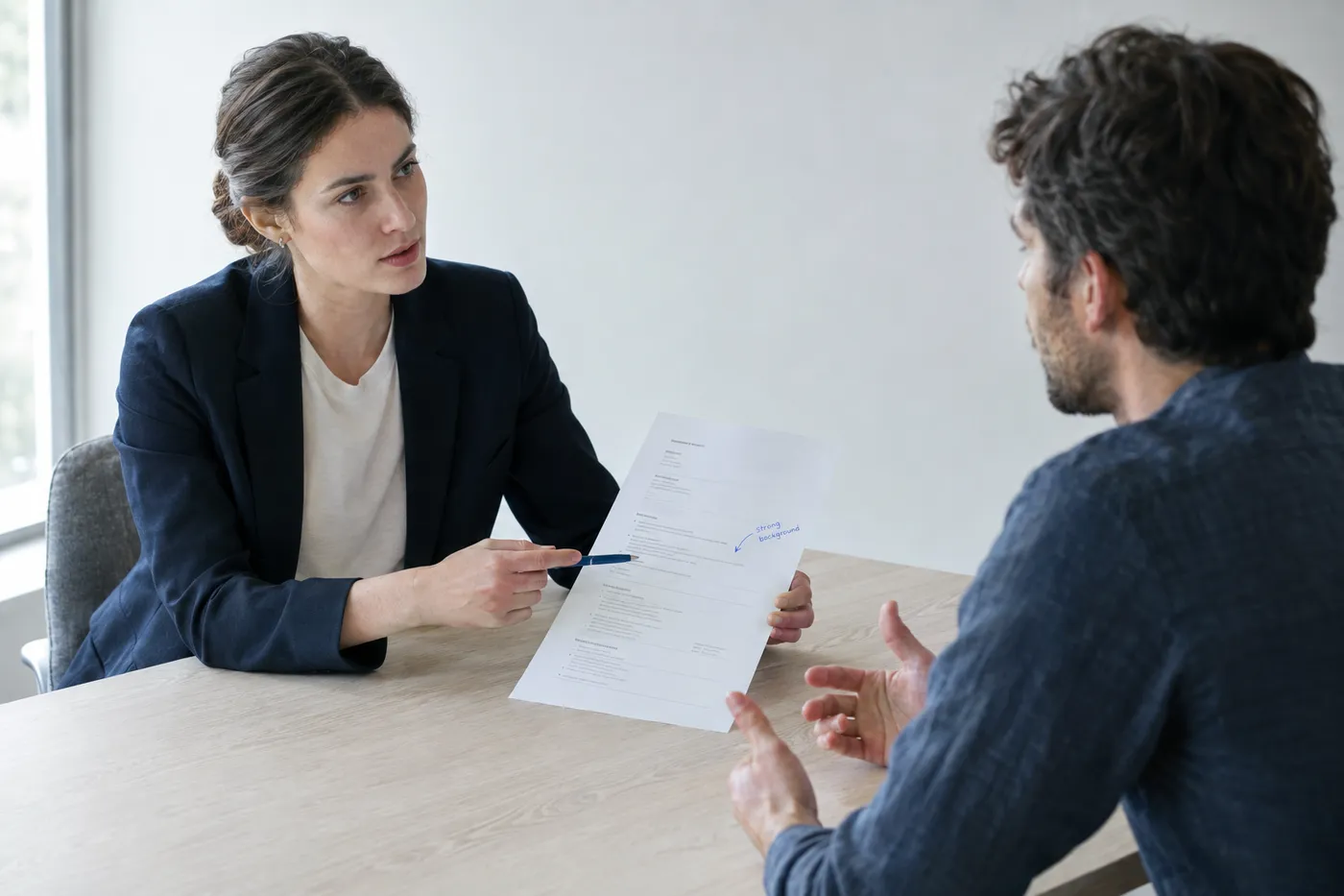 An interviewer and candidate discuss a clean, watermark-free printed resume during a candid meeting.