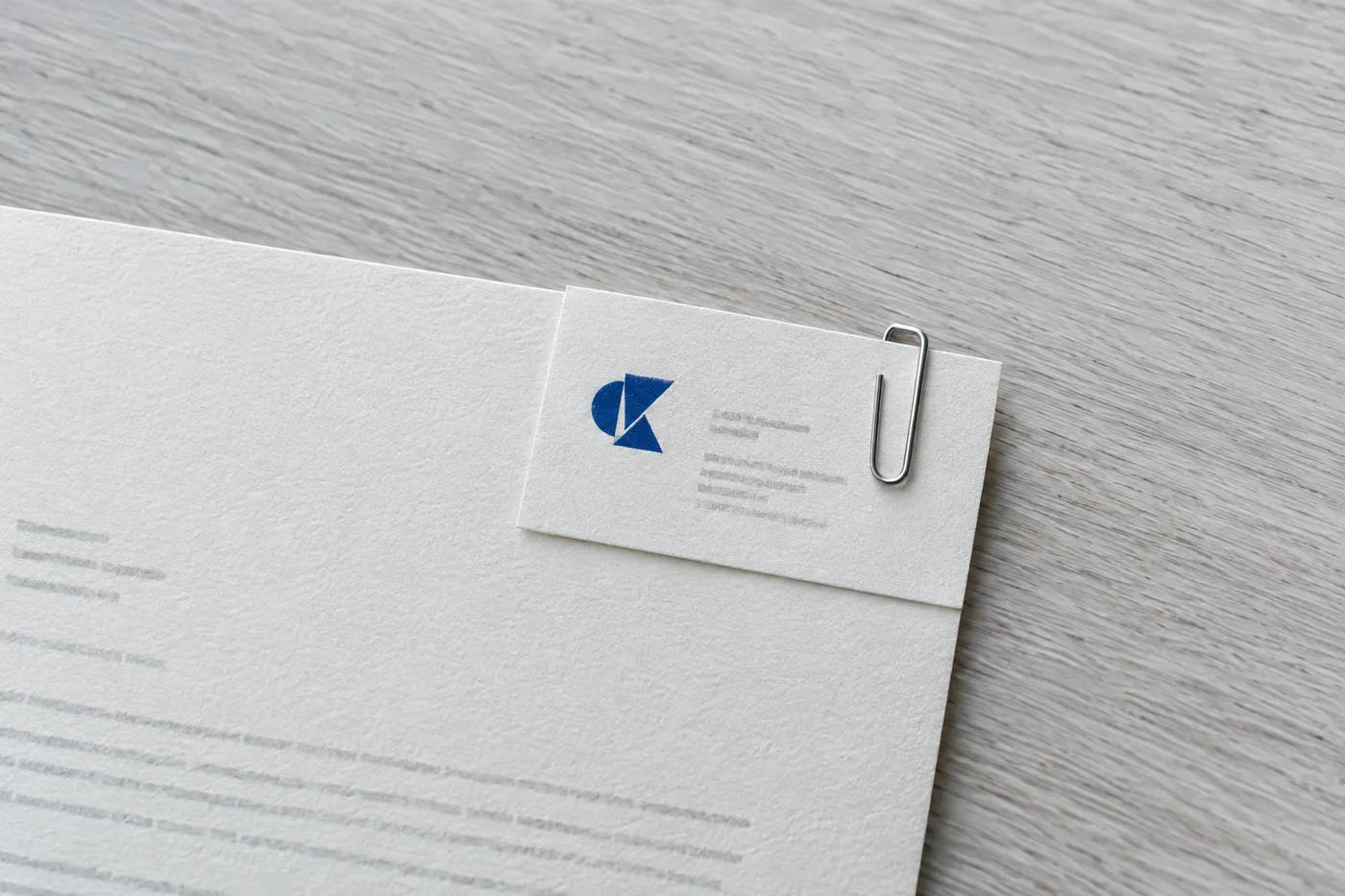 A minimalist business card paperclipped to the corner of a cover letter, symbolizing a verified professional reference.