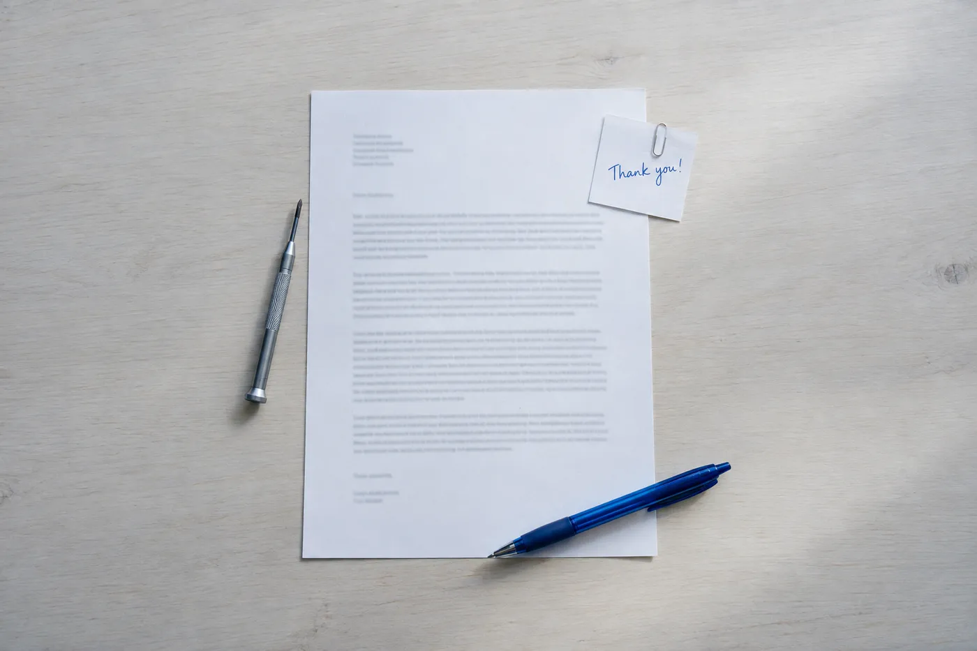 A printed cover letter on a desk, flanked by a precision screwdriver and a handwritten thank-you note in blue ink.