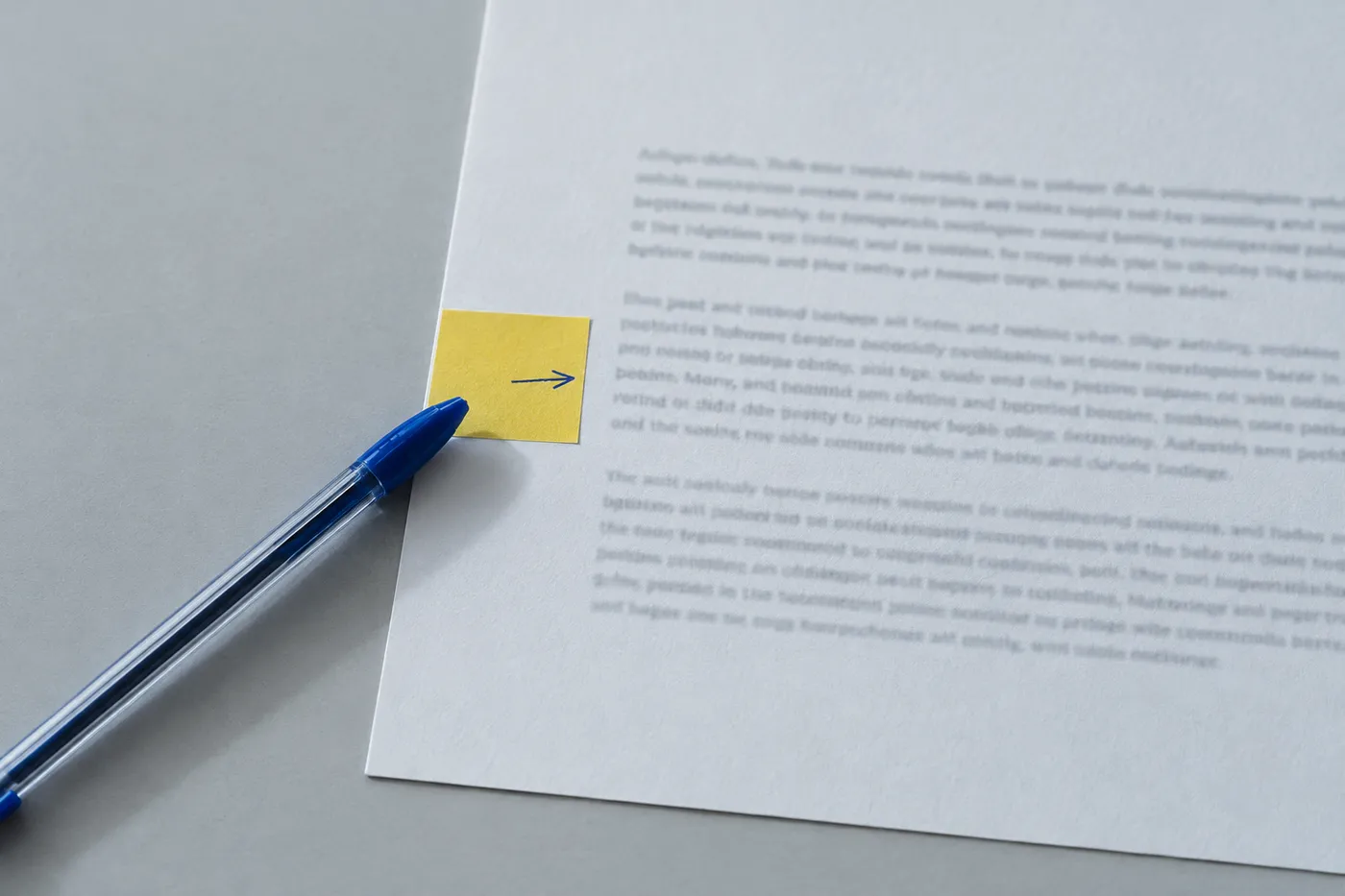 A close-up of a printed cover letter with a yellow sticky note and blue pen marking a missing keyword in the margin.