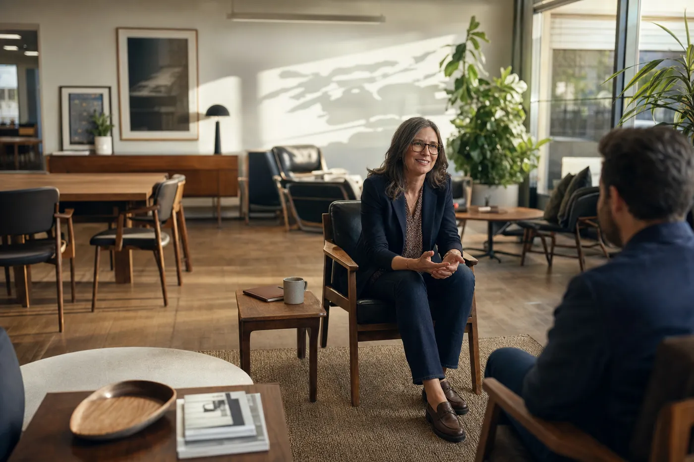 An experienced professional in a warm, modern office lounge speaks confidently during a senior-level interview.