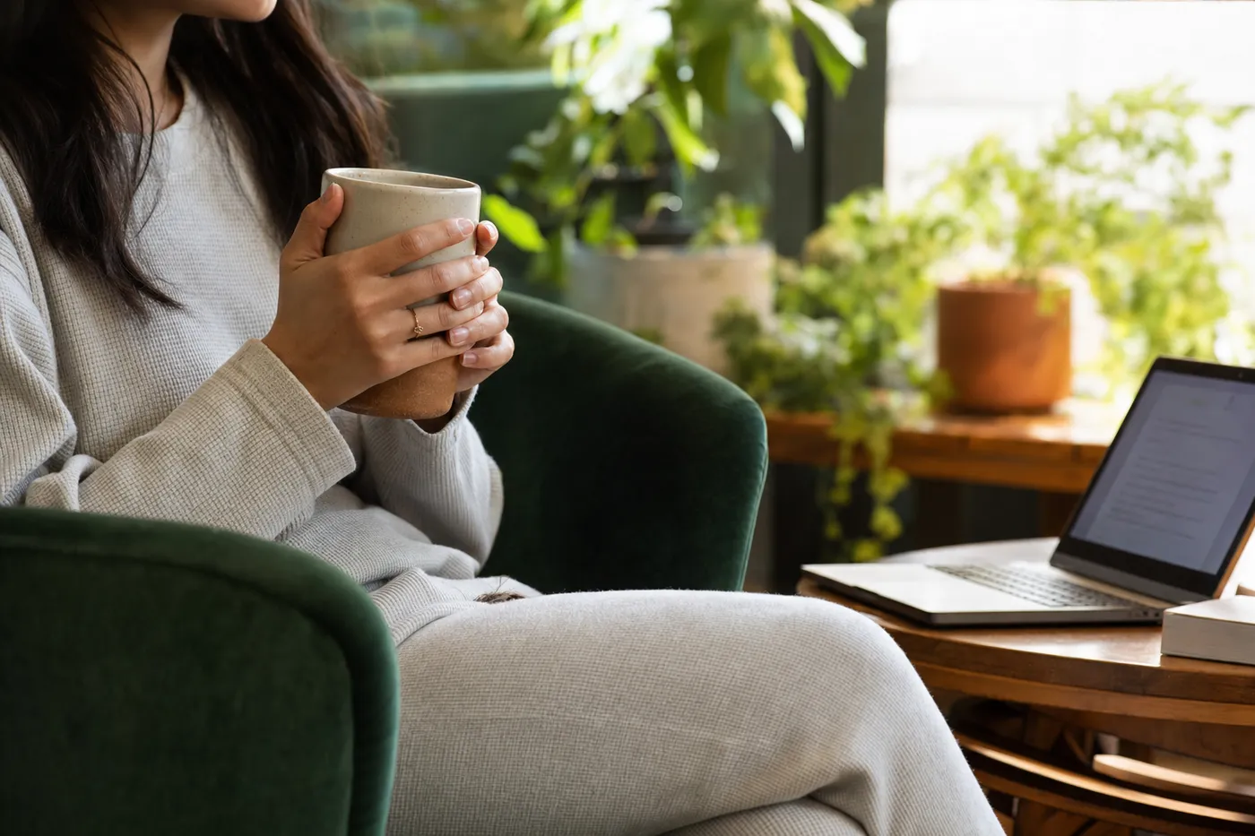A person relaxes in an armchair with a mug near an open laptop, representing the low-pressure ease of anonymous editing.