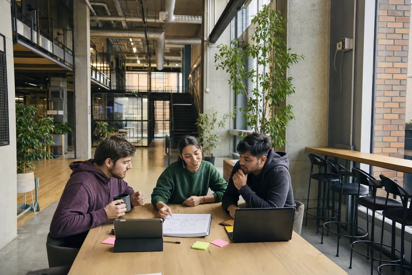 A collaborative team of young professionals brainstorms over diagrams and devices in a bright, modern workspace.