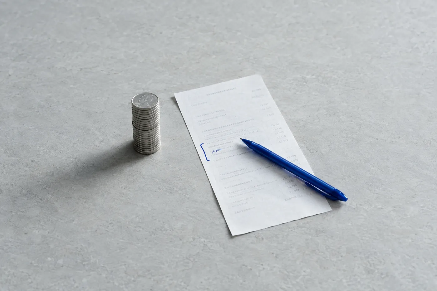 A stack of silver coins beside a transaction slip marked with blue ink, representing bank teller accuracy and service.