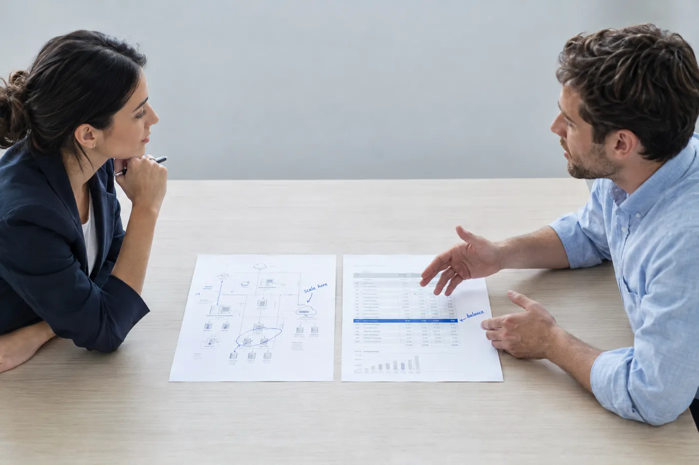 An IT manager and an interviewer discuss a technical diagram and budget sheet during a resume review.