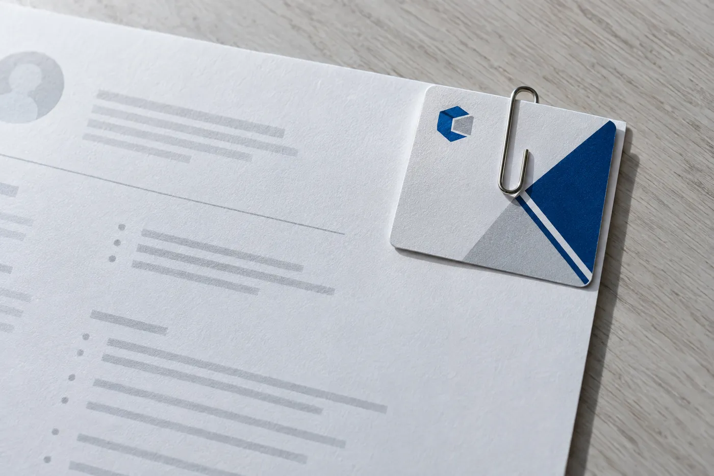 A professional certification card clipped to the corner of a printed programmer resume with a silver paperclip.