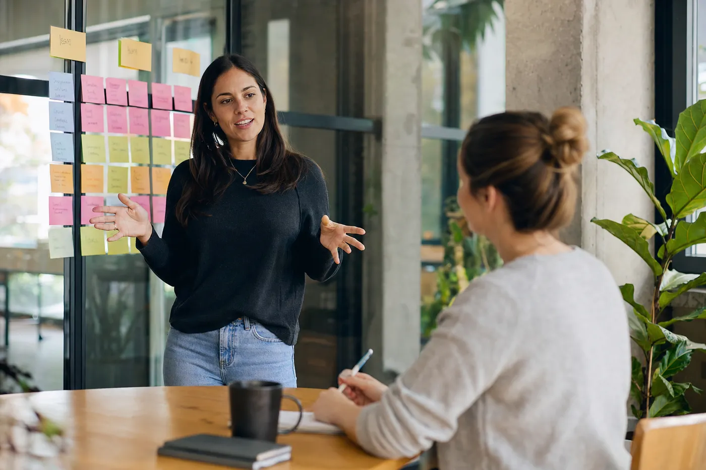 A project manager collaborating with a colleague near an agile planning board in a bright, modern office.